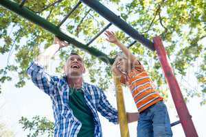 Low angle view of father and son playing on jungle gym