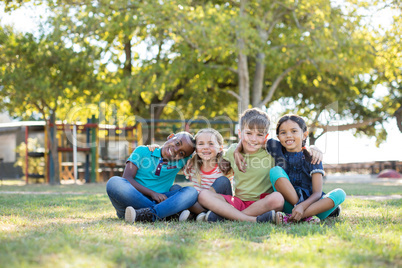 Portrait of happy children with arms around sitting at park