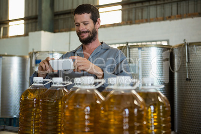 Smiling working taking a photo of olive oil bottles