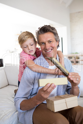 Son giving gift box to father in living room