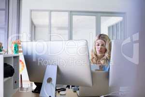 Female executive using mobile phone while working at her desk