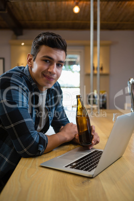 Portrait of man with laptop enjoying beer