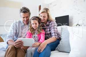 Smiling family using digital tablet together in living room