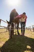 Full length of woman bending by horse on field