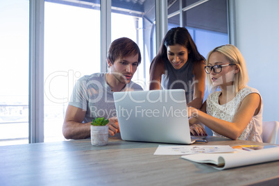 Executives discussing over laptop during a meeting