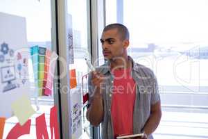 Male executive reading sticky notes on glass door