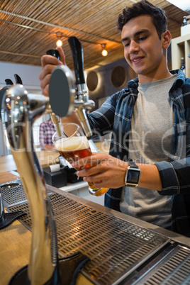 Bartender pouring beer from tap in glass