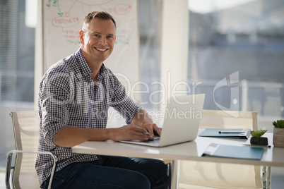 Portrait of confident executive using laptop at desk
