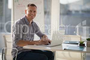 Portrait of confident executive using laptop at desk