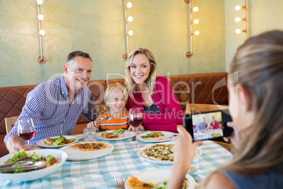 Girl photographing family through smart phone