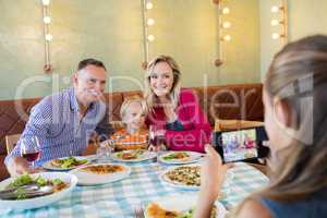 Girl photographing family through smart phone