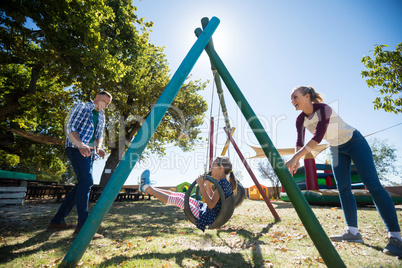 Happy mother swinging daughter at playground