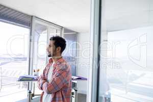 Male architect standing with arms crossed in office
