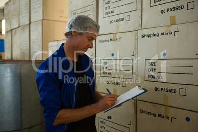 Worker writing on clipboard in olives factory