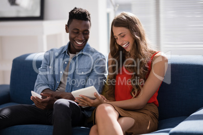 Male and female executives discussing over digital tablet in the office