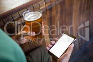 Cropped hands of man using phone while having beer