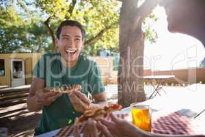 Happy man looking at friend while having pizza