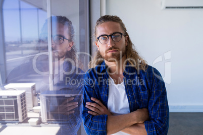 Male executive standing with arms crossed in office