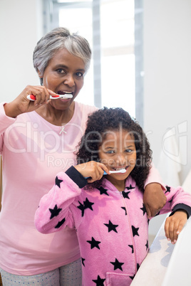 Grandmother and granddaughter brushing teeth in the bathroom