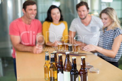 Close up of beer bottle with friends standing in background