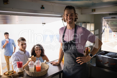 Customers and waiter standing at food truck counter