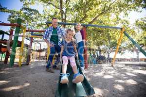 Low angle view of happy parents looking at daughter sliding