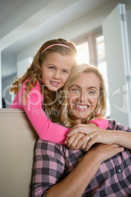 Mother and daughter embracing each other in the living room at home