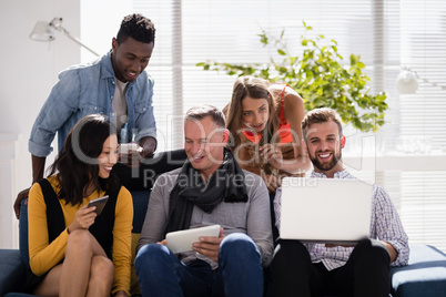 Business colleagues interacting with each other while using electronic devices