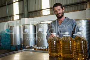 Worker standing with can of olive oil in factory