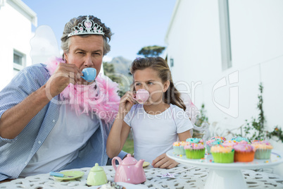 Father and daughter in fairy costume having a tea party