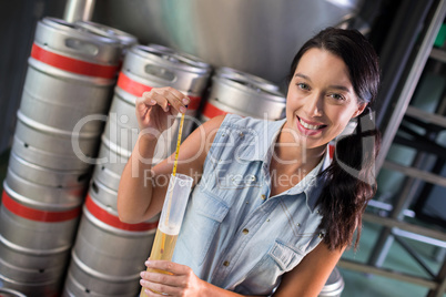 Portrait of female worker examining beer in test tube at factory