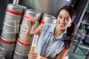 Portrait of female worker examining beer in test tube at factory