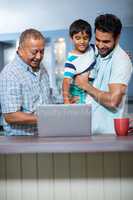 Father carrying son while standing with man