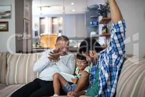 Happy grandfather and father with boy sitting on sofa