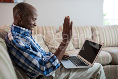 Side view of senior man video conferencing at home