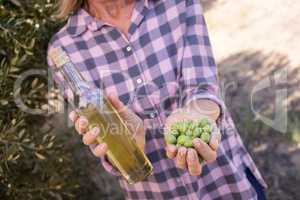 Woman holding olive oil and harvested olives