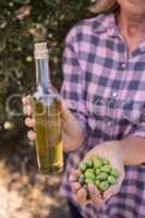 Woman holding olive oil and harvested olives