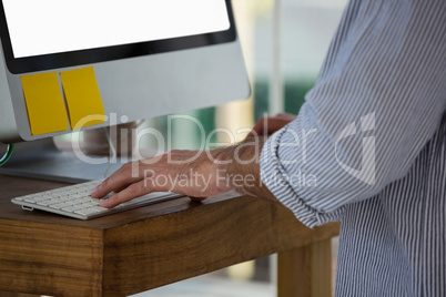 Midsection of designer using computer while standing in studio