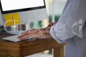 Midsection of designer using computer while standing in studio