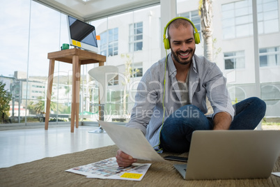 Smiling desginer holding collage using laptop at workshop