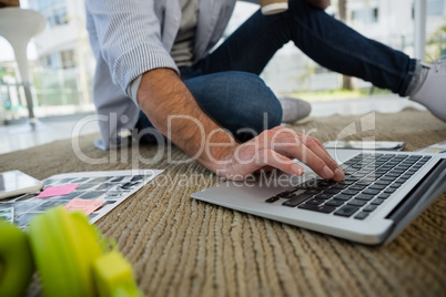 Low section of designer using laptop at office