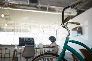 Close-up of bicycle with man working in background at office