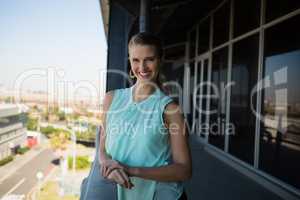 Portrait of smiling woman standing in office balcony