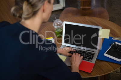 Rear view of businesswoman using laptop in office