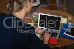 Rear view of businesswoman using laptop in office