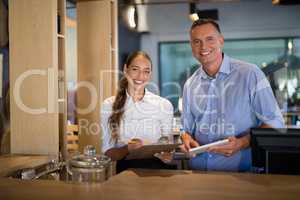 Smiling manager and bartender standing at bar counter