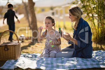 Mother and daughter blowing bubble in park