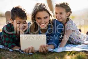 Mother and kids using digital tablet in park