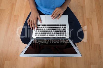 Female executive using laptop while sitting on wooden floor