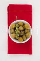 Overhead view of olives in bowl on napkin